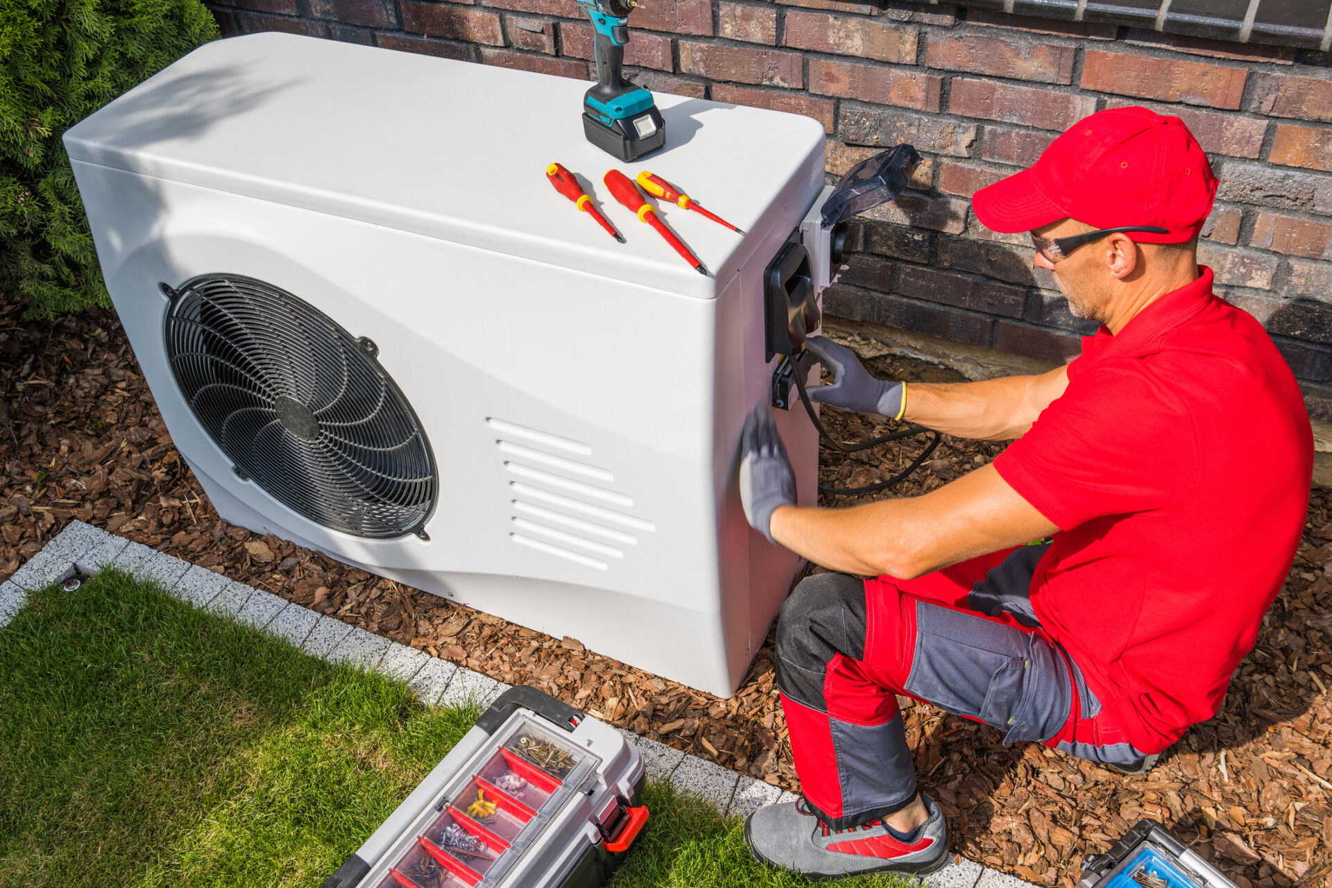 Technicus installeert buitenunit warmtepomp bij huis
