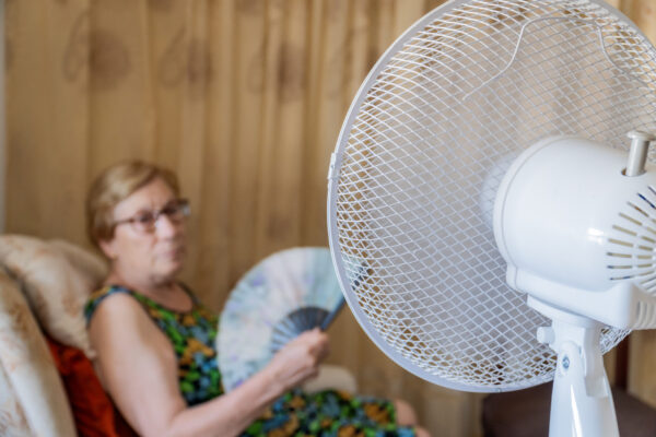 Ventilator met op de achtergrond een oudere vrouw in stoel met waaier