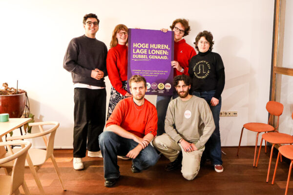 Deelnemers van de Landelijke Jongerencoalitie Wonen met het bord van de petitie in beeld. Daarop staat de tekst: "Hoge huren, lage lonen: dubbel genaaid. Landelijke Jongerecoalitie Wonen eist: meer woningen, een eerlijk loon & betaalbare huur"