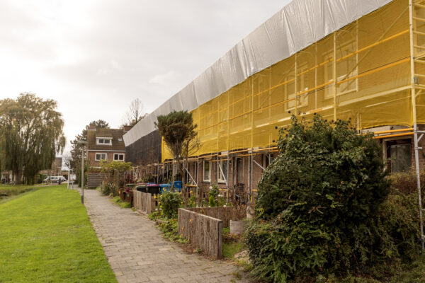 Steigers tegen de gevel van rijtje oude huurwoningen die gerenoveerd worden.